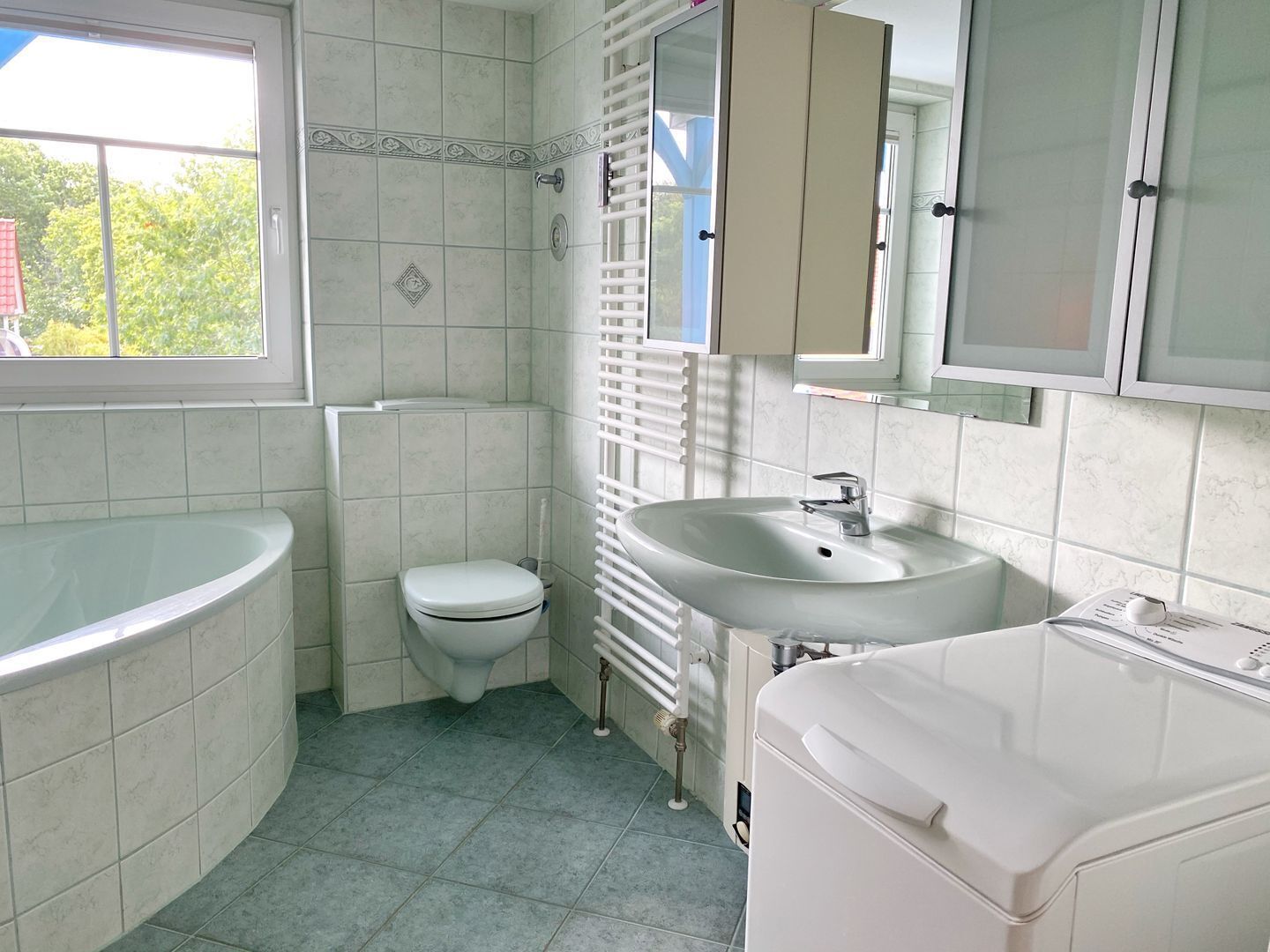 Kylpyhuone, jossa on kylpyamme, wc, pesuallas ja ikkuna.