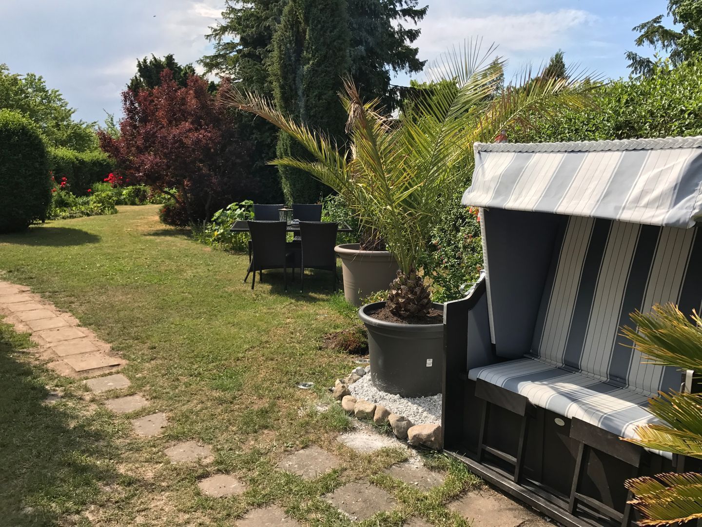 A garden with a patio area, a seating bench, and a table with chairs.