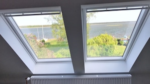 Two skylights with a view of a lake and greenery.