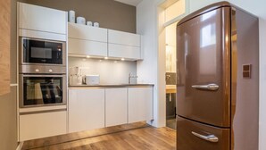 Een moderne keuken met roestvrijstalen apparatuur, witte kastjes en een houten vloer.