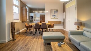 Een moderne woonkamer met een eethoek, een bank, een salontafel en een keuken op de achtergrond.