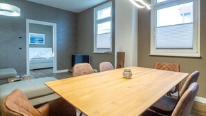Een moderne kamer met een houten eettafel, comfortabele stoelen, een televisie en een bed met uitzicht.