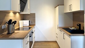Una cocina moderna con armarios blancos, encimera de madera y microondas integrado.