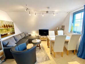 Ein modernes Wohnzimmer mit einer Couch, einem Couchtisch und einem Fernseher.