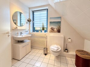 Un bagno moderno con lavandino, specchio, servizi igienici e una finestra con persiane.