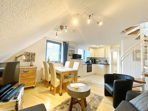 A compact living space with a dining area, kitchen, and a staircase leading to an upper level.