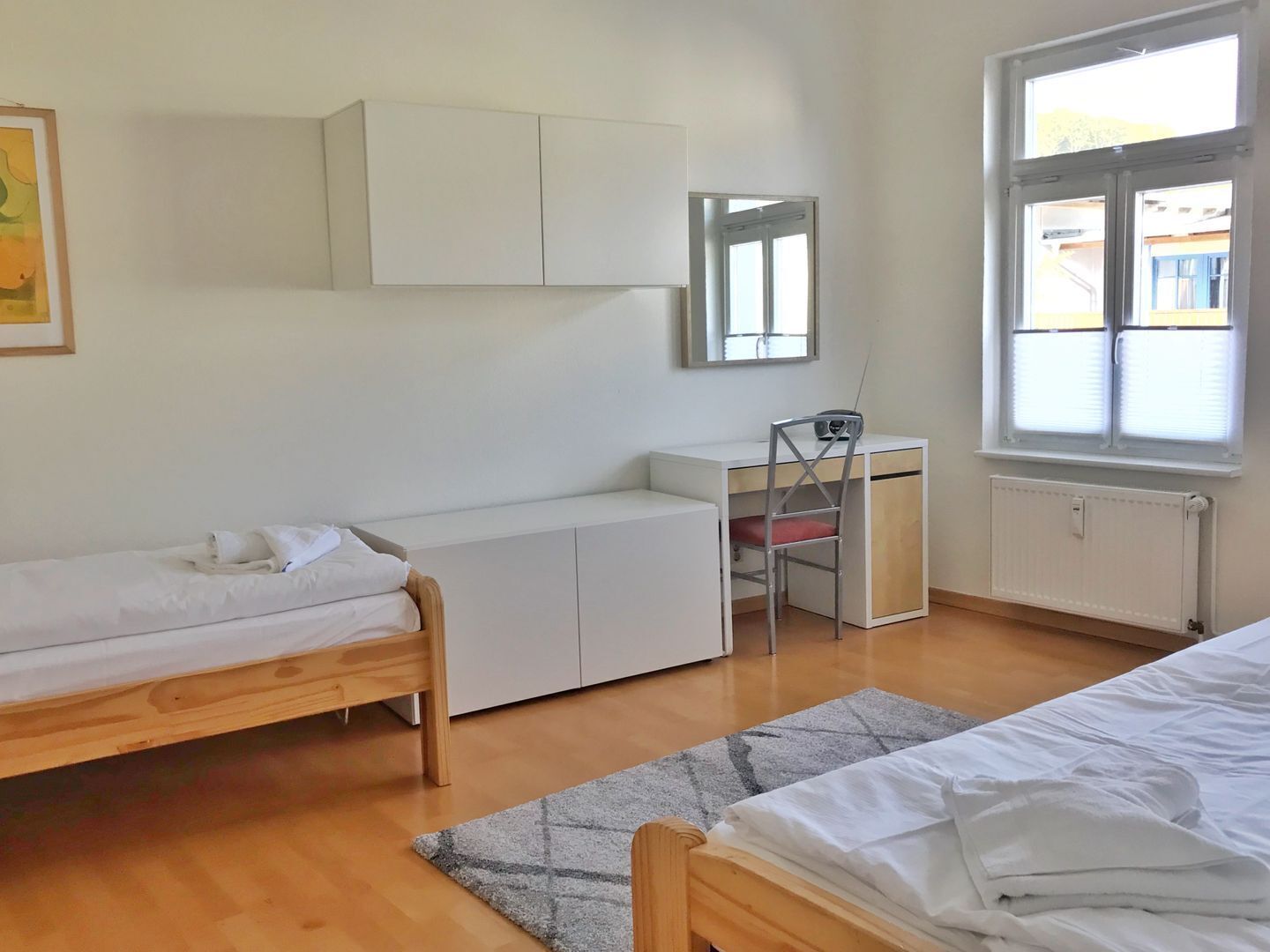 Une chambre à coucher avec un lit, un bureau, une chaise et une fenêtre.