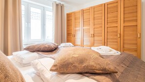 A bedroom with a bed, two pillows, a window, and wooden wardrobes. - Ferienwohnung "naurulokki" (Baabe)