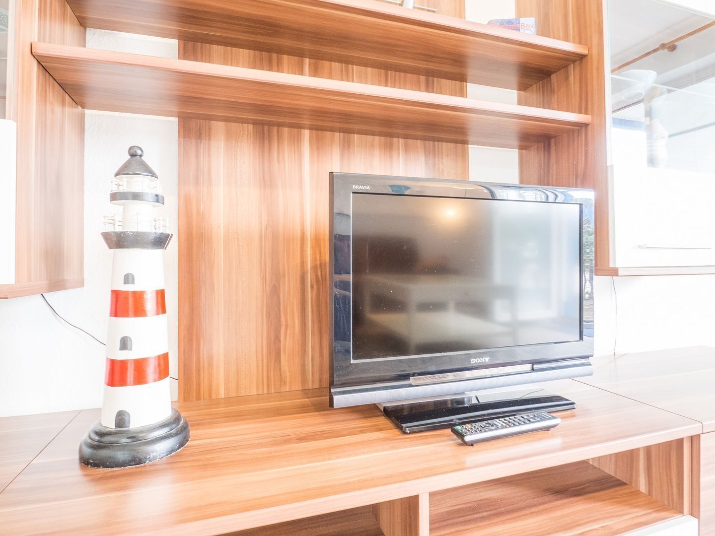 A wooden TV stand with a Sony TV and a remote control.