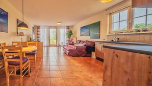 A spacious living area with a dining table, sofa, and kitchen area.