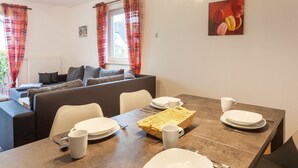 A dining area with a table set for four, a wicker basket, and a painting on the wall.