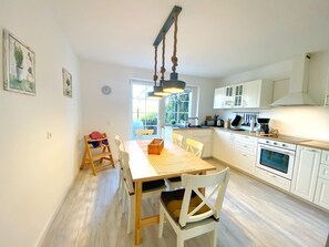 Een moderne keuken met witte kastjes, een houten eettafel en een hangende lamp.