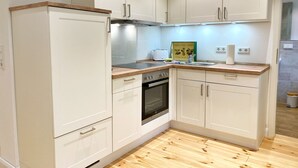 A compact kitchen with white cabinets, a built-in oven, and a wooden countertop.
