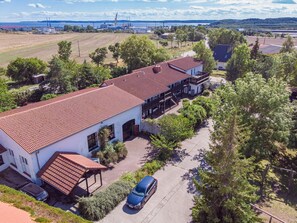 Ein großzügiges, eingeschossiges Gebäude mit rotem Ziegeldach und einer überdachten Veranda, davor ein geparktes Auto.