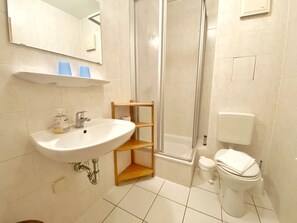 Ein Badezimmer mit Waschbecken, Spiegel, Dusche und Toilette.