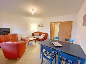 Ein Wohnzimmer mit einer Couch, einem Tisch und einem Fernseher.