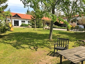 Un espacio al aire libre con césped, una banca de madera y un columpio.