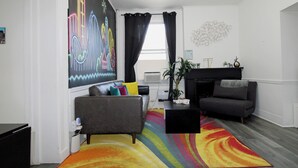 A living room with a colorful striped rug, a grey sofa, a black coffee table, and a fireplace.
