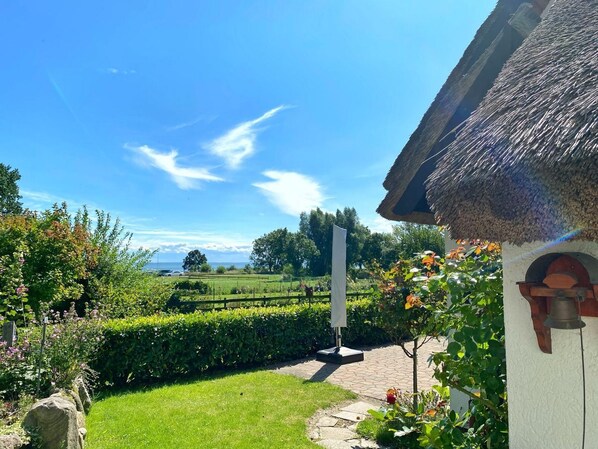 A thatched-roof building with a stone pathway leading to a flagpole.