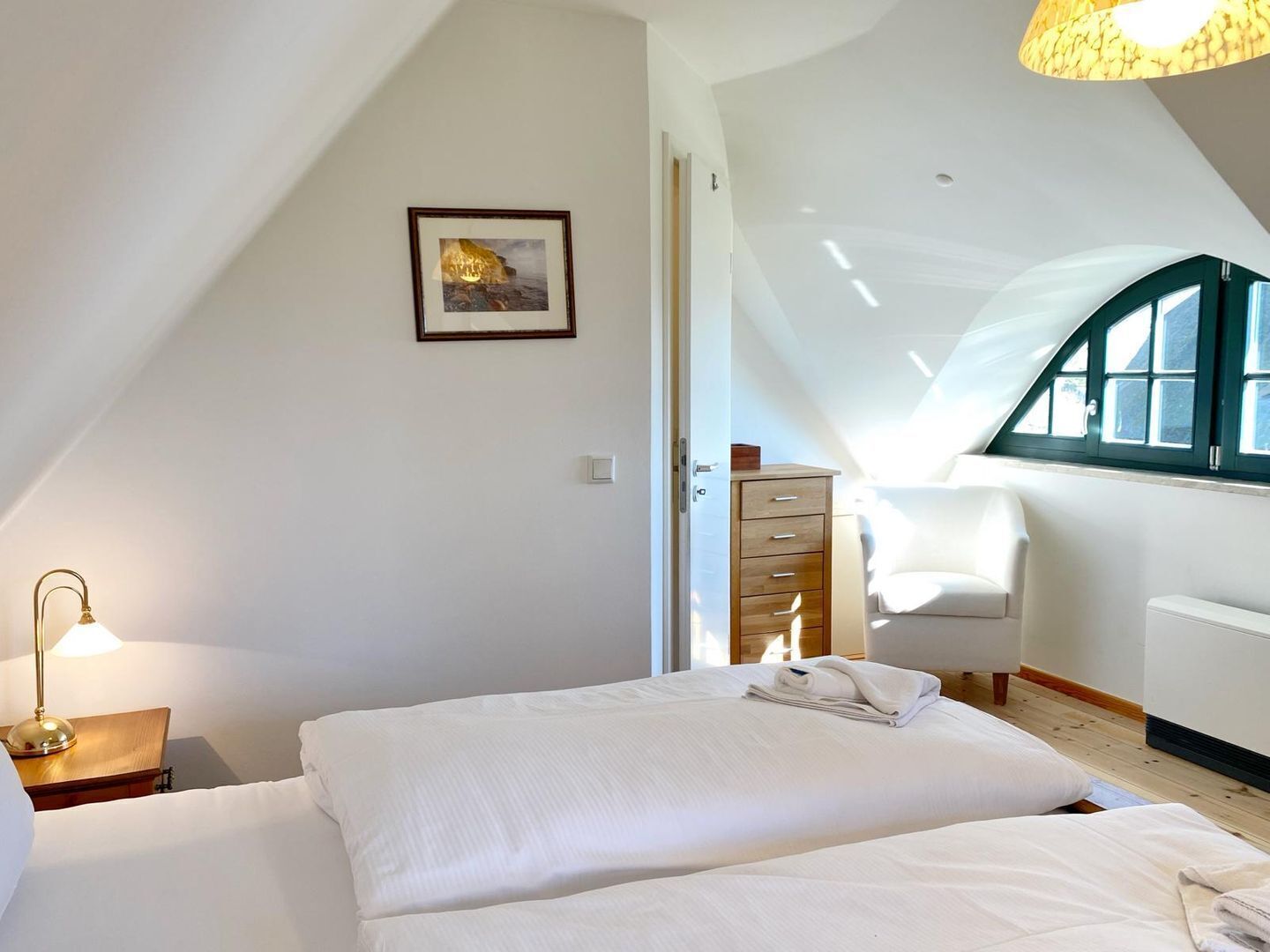 A bedroom with a bed, a nightstand, a dresser, a chair, and a window with a view.