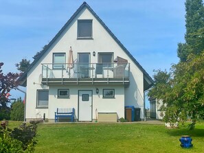 Une maison à deux étages avec un balcon, une porte d’entrée et un petit jardin.