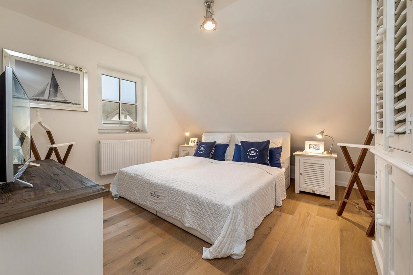 Un dormitorio con una cama grande, una ventana, un escritorio con una computadora y un radiador.