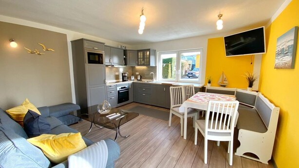 A compact living space with a kitchenette, a dining area, and a seating area with a sofa and chairs.
