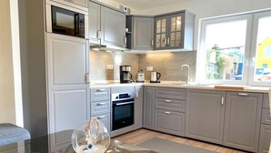 A modern kitchen with grey cabinets, a built-in oven, a microwave, and a coffee maker.