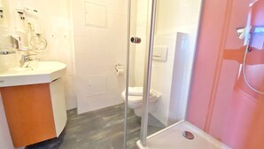 A modern bathroom with a glass shower enclosure, a white sink, and a toilet.