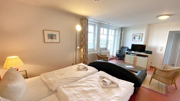 A hotel room with two beds, a desk with a computer, a TV, and a chair.