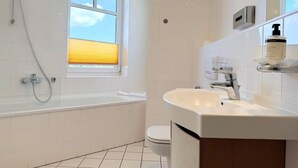 Une salle de bain moderne équipée d’une baignoire, de toilettes et d’un lavabo.