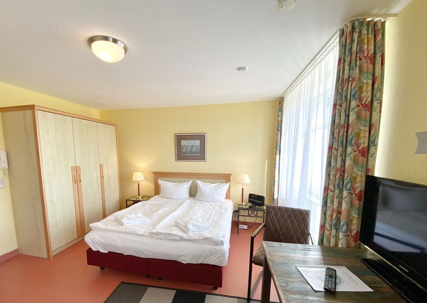 Une chambre d’hôtel comprenant un lit, des tables de chevet, un téléviseur, un bureau et une chaise.