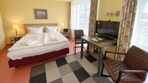 A hotel room with a bed, a TV, a desk, and a chair.