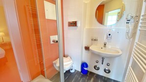 A bathroom with a glass shower enclosure, a white sink with a mirror, and a toilet.