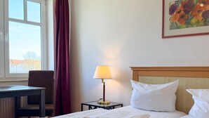 Ein Hotelzimmer mit einem Bett, einem Schreibtisch, einer Lampe und einem Gemälde.