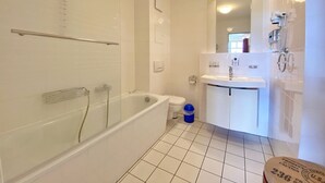 Ein Badezimmer mit Badewanne, Toilette und Waschbecken, alles in Weiß.
