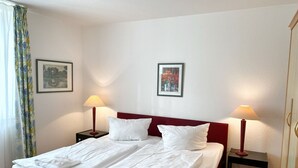 A hotel room with a bed, two bedside tables, two lamps, and two framed pictures on the wall. - Apartment 307 - Rondell an der Jasmundtherme - Neddesitz an der Jasmundperle / (Sagard)