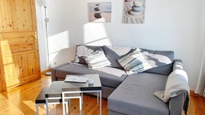 Ein modernes Wohnzimmer mit einer grauen Couch, einem kleinen Tisch und einer Holztür.