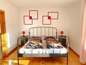 A single bed with a metal frame, two bedside tables with red lamps, and a wooden floor. - Seaside Appartements, "Red" - Sassnitz - Seaside Appartements (Sassnitz)