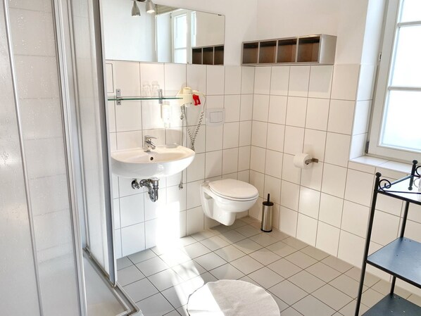 A bathroom with a sink, toilet, and a shower area. - Seaside Appartements, "Red" - Sassnitz - Seaside Appartements (Sassnitz)