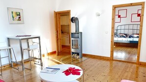 Moderni olohuone, jossa on pyöreä valkoinen pöytä, punainen sohva ja avoimen oven kautta näkyvä keittiötila.