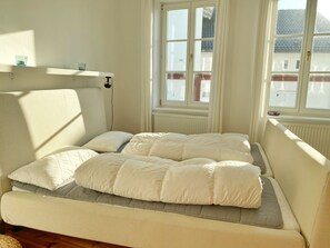 Ein Schlafzimmer mit Bett, Fenster und Heizkörper.