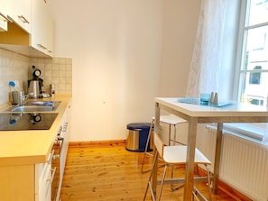 A compact kitchen with a sink, stove, and a window with curtains.