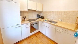 Une cuisine moderne avec des armoires blanches, un four encastré, une plaque de cuisson et un évier.