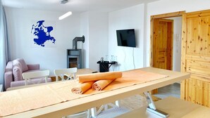 A modern room with a wooden table, a sofa, a TV, and a fireplace.