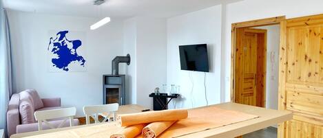 Quarto moderno com uma mesa de madeira, um sofá, uma TV e uma lareira.