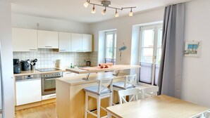 A modern kitchen with white cabinets, a central island with seating, and a dining table.