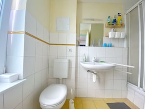 A small bathroom with a toilet, a sink, and a shower.