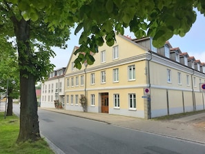 Ein zweistöckiges Gebäude mit gelber Fassade, einer Holztür und einem Verbotsschild für Parken.
