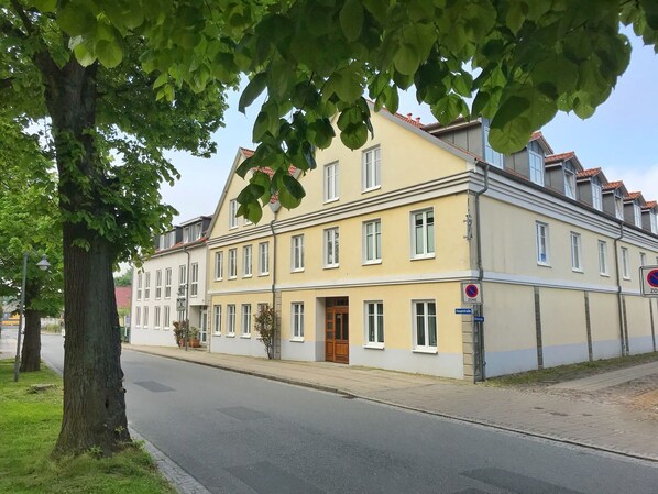 A two-story building with a yellow facade, a wooden door, and a 'no parking' sign.